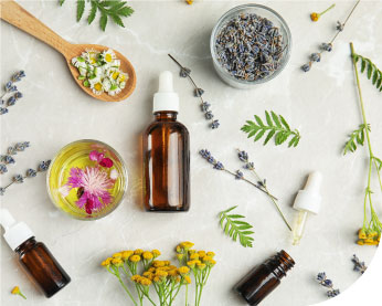 three dropper bottles lay next to botanical essential oil ingredients